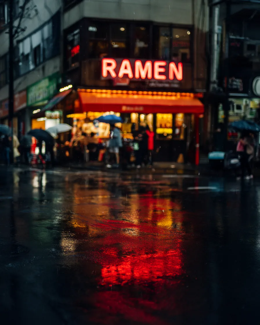 Rainy Tokyo street at night with a red neon RAMEN sign and people holding umbrellas.
