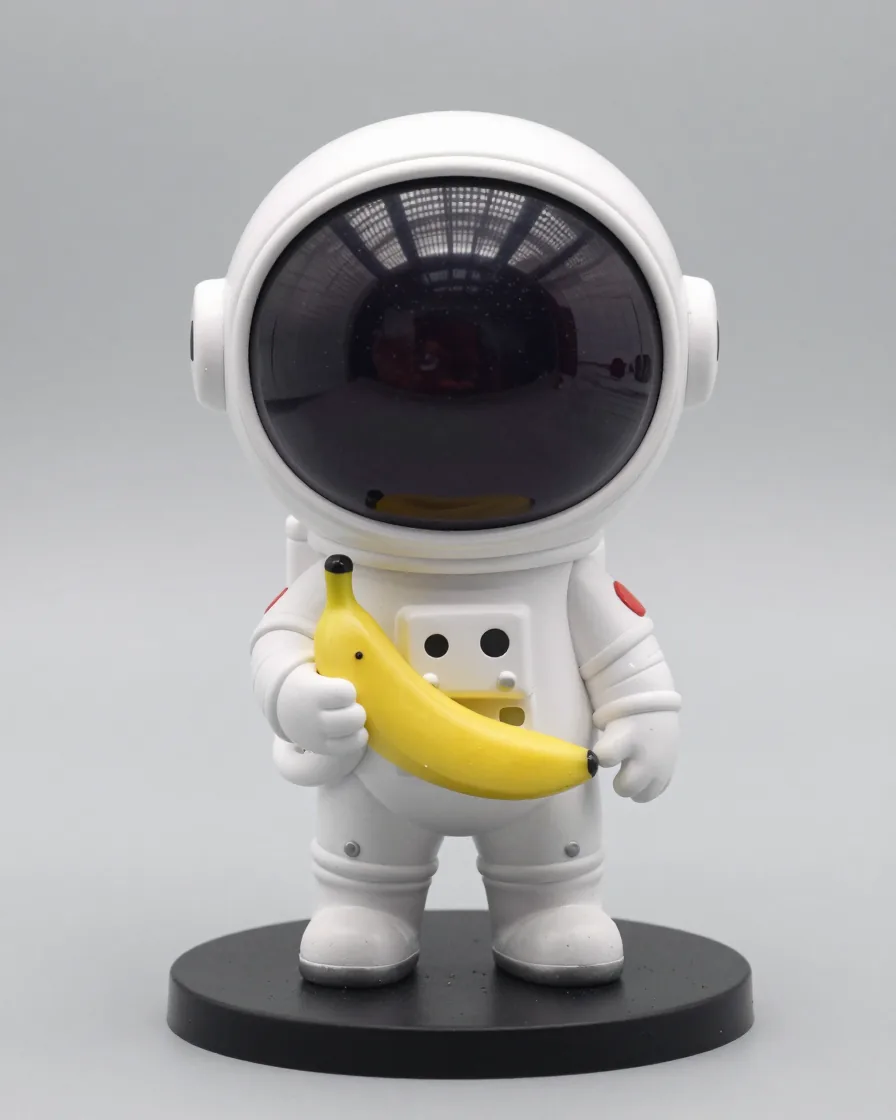 Glossy collectible vinyl astronaut figure holding a banana on a round display base.